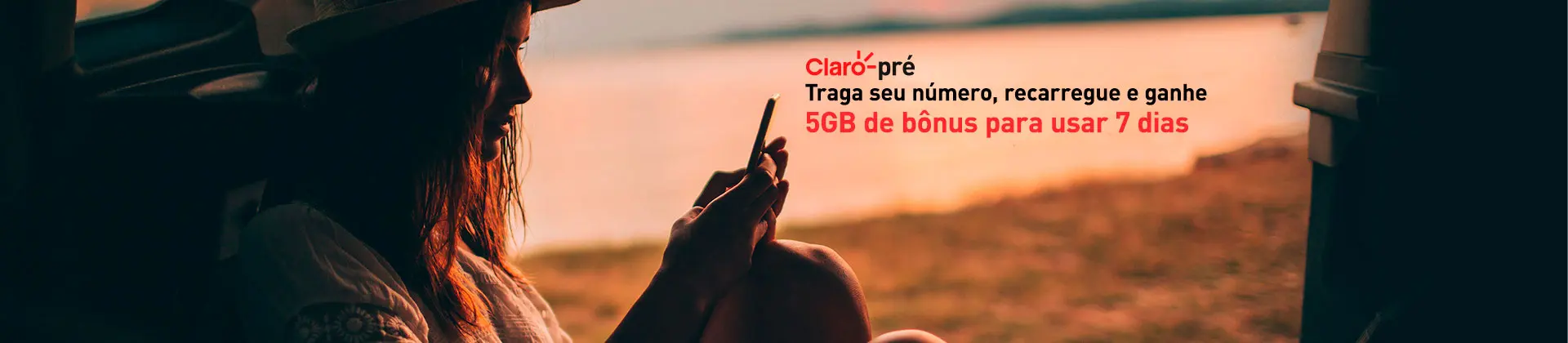 		 Foto em ambiente externo com sombra. Mulher jovem sentada no chão mexendo no celular. Na imagem há o texto: Claro pré. Traga seu número, recarregue e ganhe 5GB de bônus para usar por 7 dias