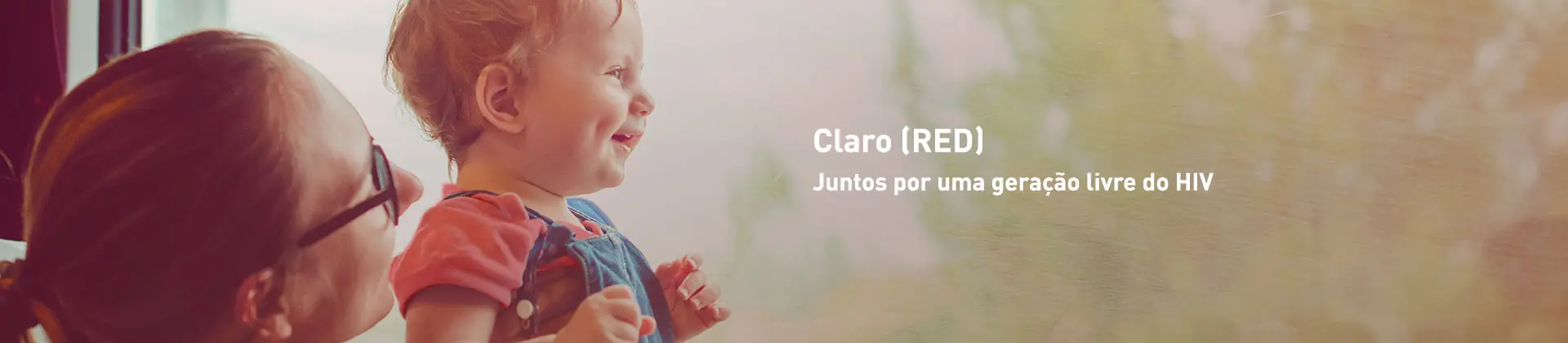 Uma moça de cabelos presos usando óculos segurando um bebê sorrindo com o escrito Claro RED: Juntos por uma geração livre do HIV