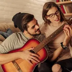 Jovem tocando violão para a namorada.