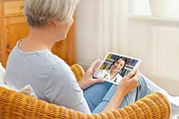 Imagem de uma senhora com um tablet nas mãos.