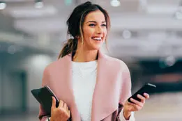 Imagem de uma moça sorrindo segurando um celular.