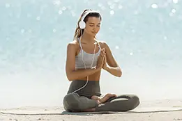 Imagem de uma moça meditando com fones de ouvido.