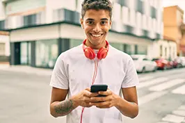 Imagem de um rapaz sorrindo enquando mexe no celular.