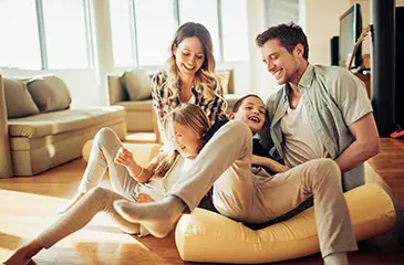Imagem de uma família brincando em uma sala de TV.