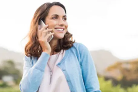 Imagem de uma moça sorrindo com um celular no ouvido.