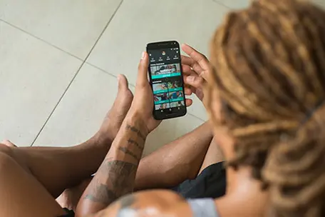 Imagem de um rapaz em desfoque na foto com um celular nas mãos.