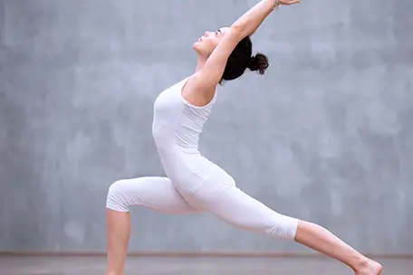 Imagem de uma moça vestindo roupas brancas praticando exercícios.